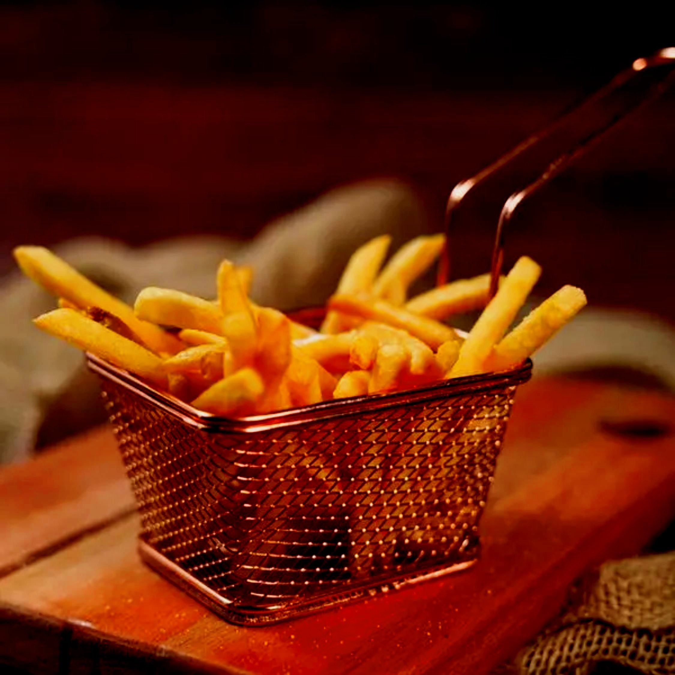 Batata frita num cestinho de metal sobre a tábua
